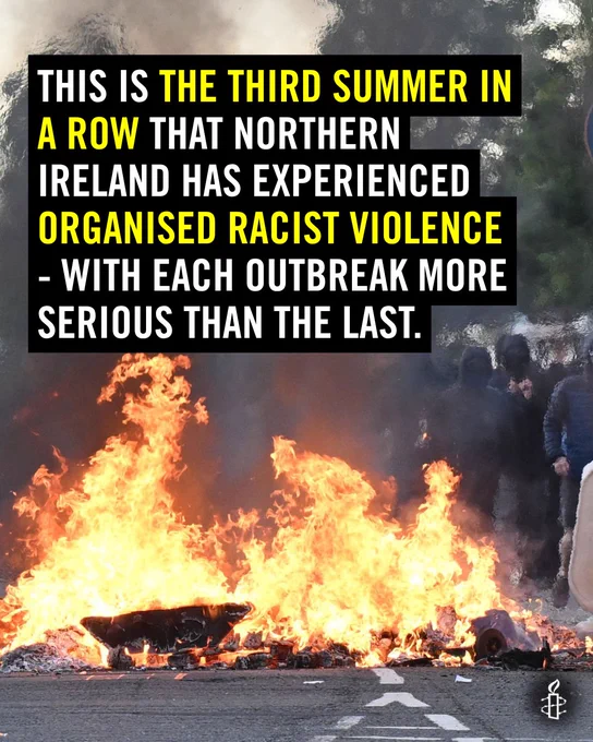 An image of a road with a car on fire. Copy that reads: This is the third summer in a row that Northern Ireland has experienced organised racist violence - with each outbreak more serious than the last.