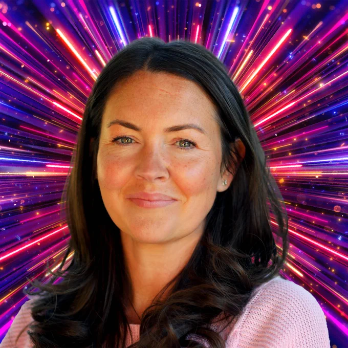 A woman with long dark hair smiles to camera, set against a glittering background with rays of red, pink, purple and blue light