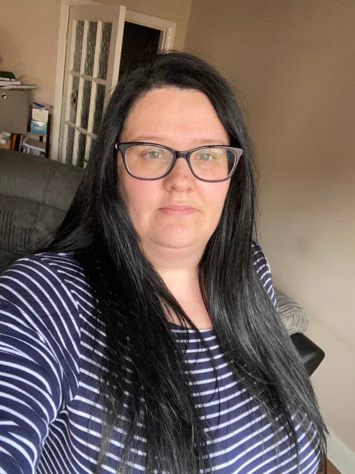 A selfie by a person with long black hair and glasses who is wearing a navy and white striped shirt.