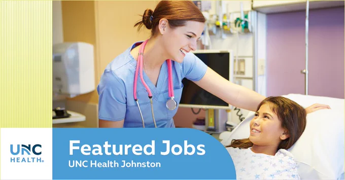 A healthcare professional in scrubs with a stethoscope interacts with a young patient lying in a hospital bed. 
