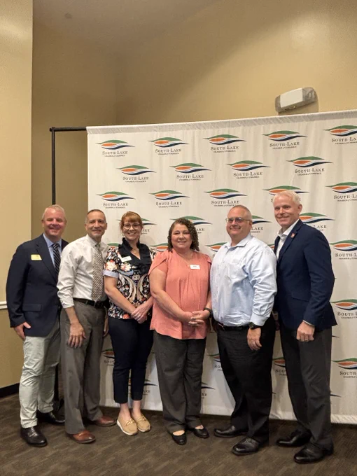 A group of six people posing together at a South Lake Chamber of Commerce event. The backdrop displays the organization's logo.