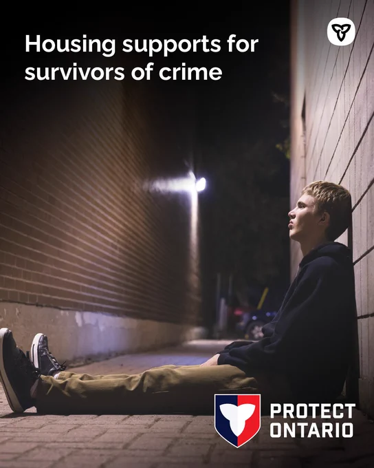 A young man in an ally way sitting with his back to the wall