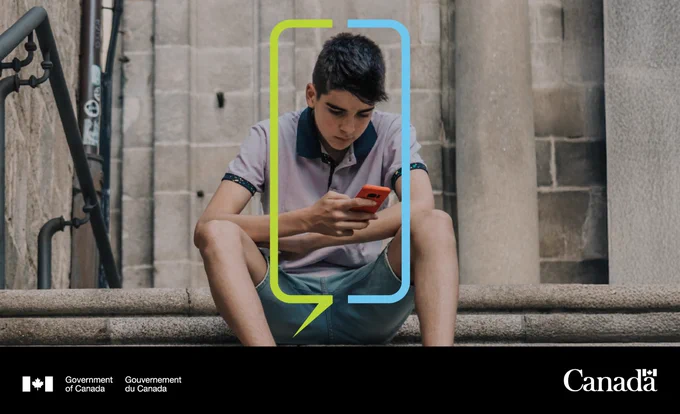 Young child sitting on steps, looking at his phone.