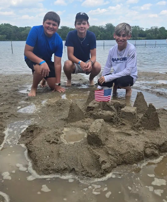 students with sandcastle at beach