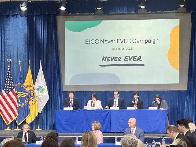 Meeting participants discuss the Federal Elder Justice Action Plan beneath a presentation screen displaying “EJCC Never EVER Campaign” and “June 15–26, 2025.” Attendees, including Mary Lazare, ACL’s Principal Deputy Administrator, are seated at conference tables in the foreground, with U.S., HHS, and HUD flags visible beside the stage.