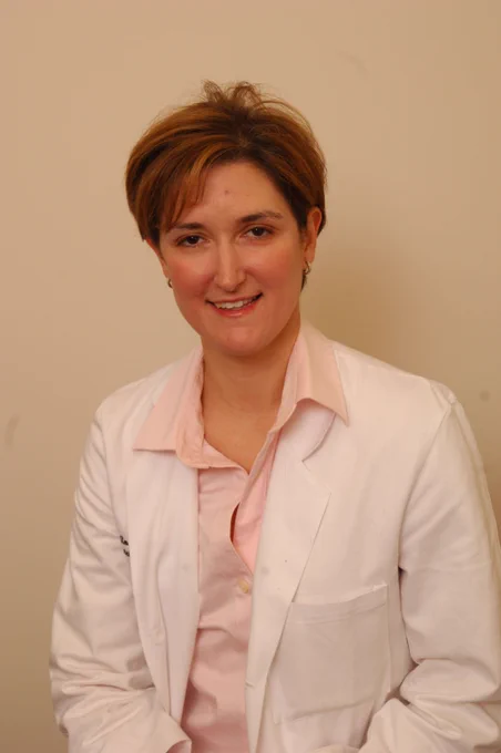 A woman in a white lab coat and pink blouse.