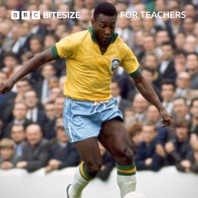 A photograph of Brazil’s Pelé wearing a yellow and green football shirt, kicking the ball during a football match, with the crowd watching behind.