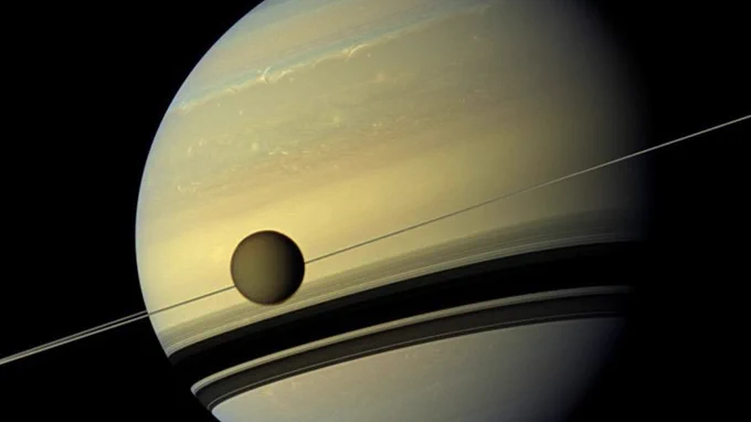 Titan, Saturn's largest moon orbiting the gas giant.