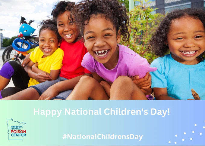 Four young children sit close together outdoors, facing the camera and smiling. A bicycle with a helmet is visible behind them on the left, and greenery and a building appear in the background.
Text on the image reads: “Happy National Children’s Day!” and “#NationalChildrensDay.” A logo in the lower left corner reads “Minnesota Regional Poison Center.”