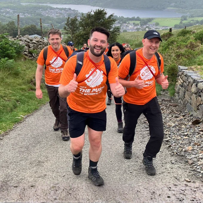 Photo of three Back Up supporters smiling at the camera and giving a thumbs up whilst taking part in The Push 2025.