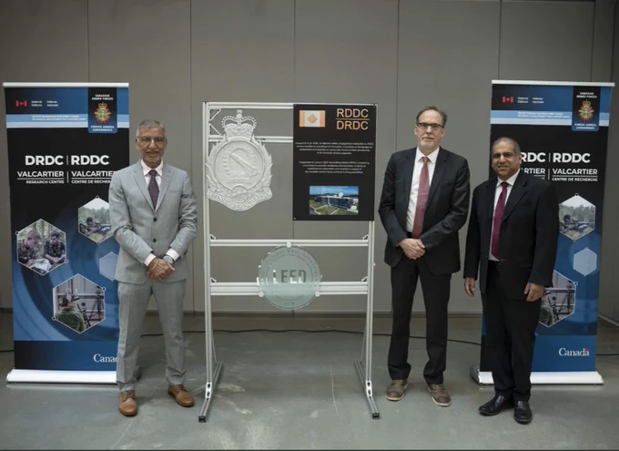 Three members from the Defence Research and Development Canada (DRDC) team standing by a display stand, looking straight at the camera.