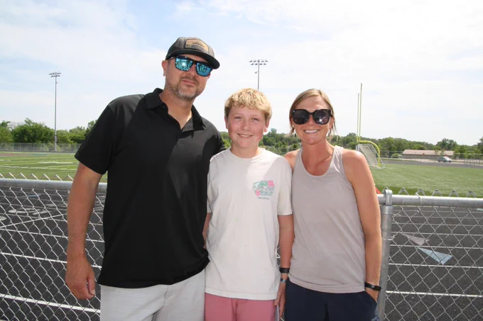 Carter Blackketter smiling and standing in the middle of his mom and dad. 