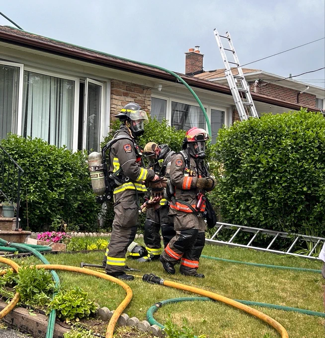 Fire crew on lawn outside of a house.