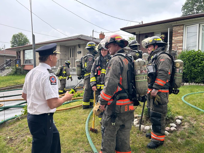 Platoon Chief speaking to crews on lawn outside house.
