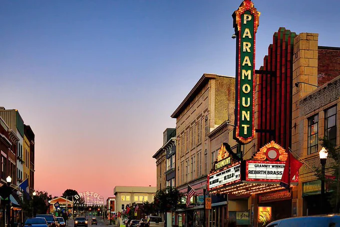 Paramount Theater at First Light is a Fine Art piece showcasing the Paramount Theater on State Street in Bristol Tennessee and Virginia with early morning color, warm architectural textures, and the illuminated Bristol sign in the distance. From the Fine Art Gallery of Shelia Hunt.