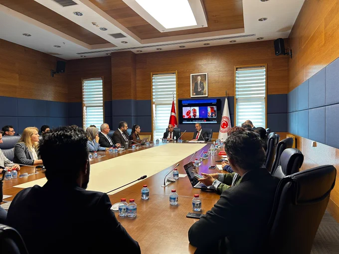 TBMM’de gerçekleştirilen toplantıda Komisyon Başkanı Mehmet Muharrem Kasapoğlu başkanlığında uzmanlar, akademisyenler ve davetlilerin katılımıyla komisyon raporunun yazım süreci değerlendiriliyor. Uzun toplantı masasının etrafında bir araya gelen katılımcılar istişareleri takip ederken, arka plandaki ekranda çevrim içi bağlantıyla toplantıya katılan uzmanlar görülüyor.
