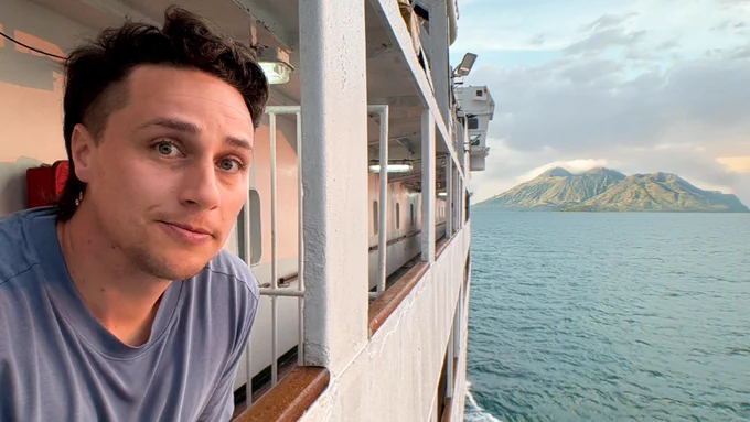 Michael Downie on a ferry with a mountainous island in the distance.