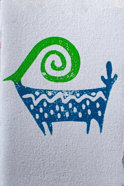 A vibrant abstract illustration of an animal with curly horn on a textured fabric.