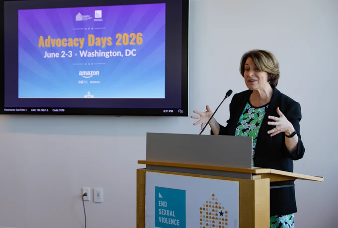 A woman gesturing behind a podium.