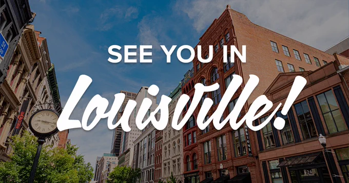 A street in Louisville with historic brick buildings and a clear blue sky. A clock on a lamppost is visible on the left. Text overlaid: "See You in Louisville!"