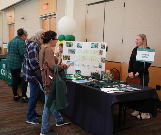 Visitors gathered around Viking Crew table. 