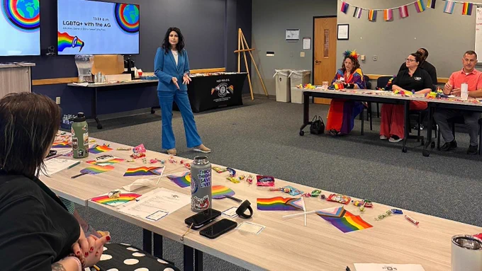 Attorney General Dana Nessel speaking in front of the MI State Police Pride E.R.G. in a conference room. 