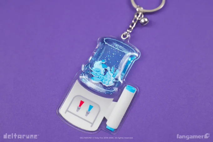 A photo of the Holy Water keychain from Fangamer's DELTARUNE collection against a purple background. It's a keychain shaped like a water cooler, with an illustration showing red and blue taps and a sleeve of disposable cups on this side. The jug of the water cooler is a squishy charm filled with glitter with a Mizzle charm inside; it's blue on this side.