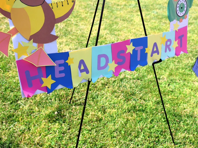A sign displaying the word "Headstart" in bold letters against a grassy background.