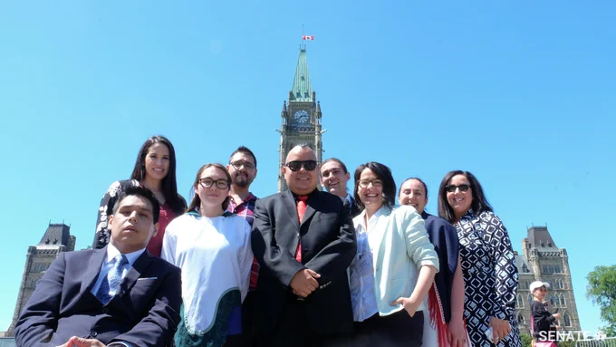 A group of Voices of Youth Indigenous Leaders participants stands in front of the Peace Tower.