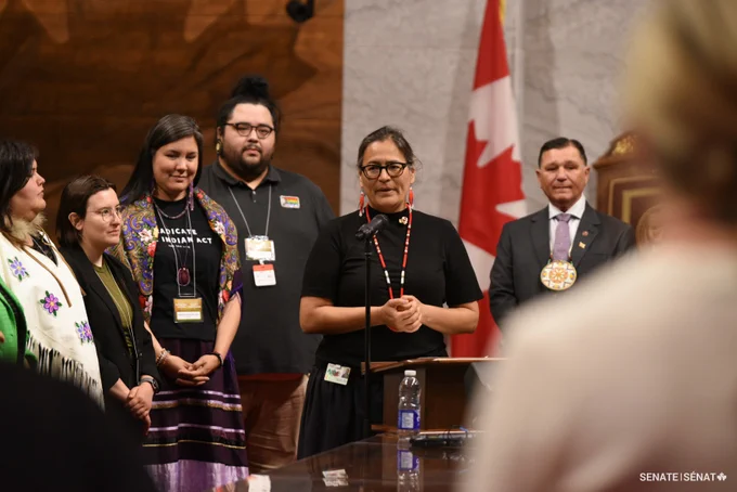 A group of people stands in the Senate Chamber. 