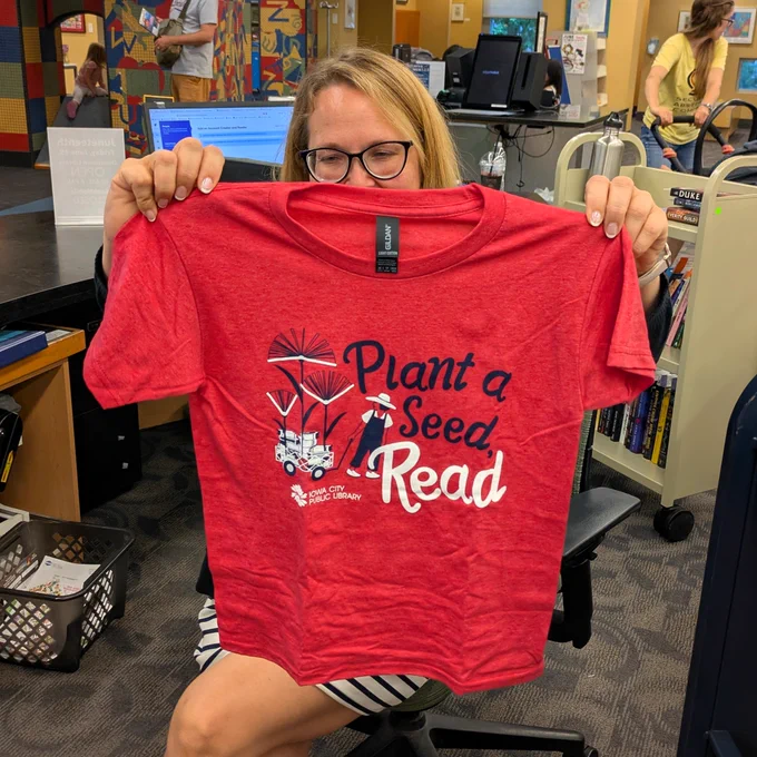 A red t-shirt that reads "Plant a Seed, Read"