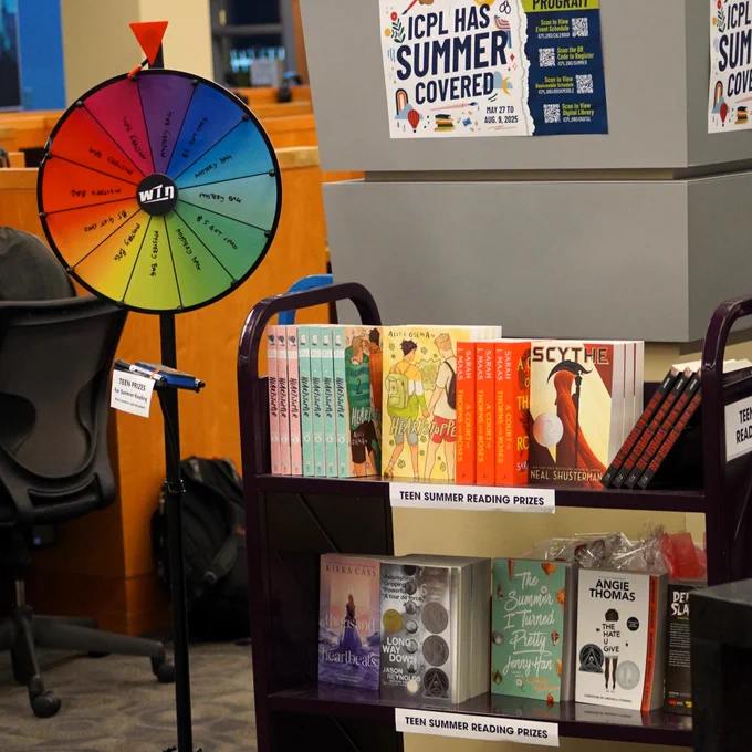 A rainbow spinning wheel and a book cart full of free books as prizes for teens.