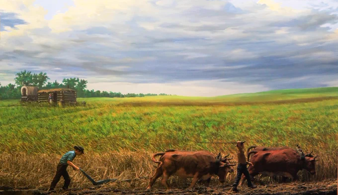 Diorama of a homesteader plowing a field with a team of oxen. A house and a wagon stand in the background.