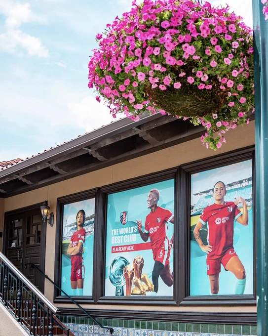 Full view of the window signage featuring Croix, Temwa, and Debinha with flowers in the photo 