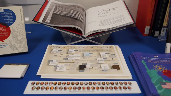 Pictured is a photo of U.S. History book, a poster that reads how a bill becomes a law and a ruler that features faces of U.S. Presidents on it. 