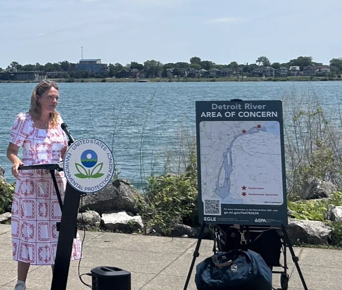 Environmental Protection Agency Midwestern Regional Director Anne Vogel standing next to poster on easel at Detroit River Area of Concern event speaking to audience.