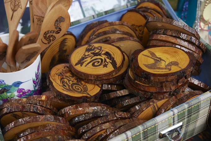 Stack of wooden coasters with intricate animal and bird engravings displayed in a rustic container.