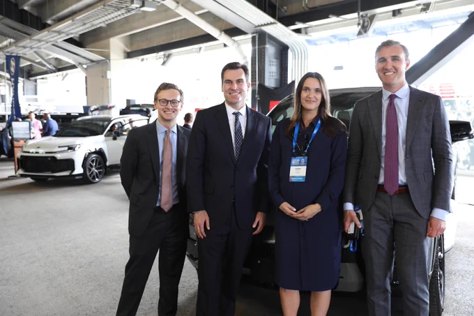 Group photo featuring Under Secretary William Kimmitt standing in front of a car.