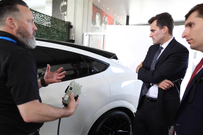 Photo of Under Secretary William Kimmitt looking at a car on a show floor.