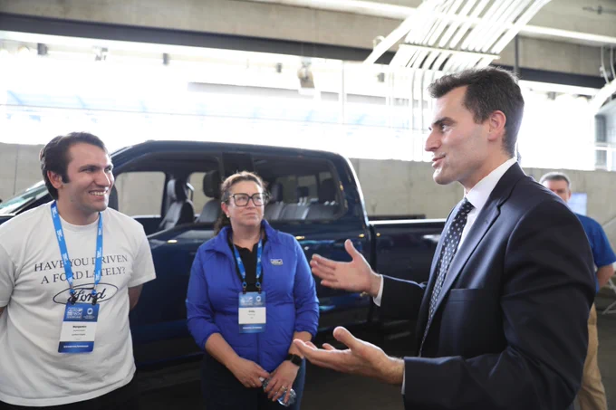 Photo of Under Secretary William Kimmitt looking at a car on a show floor and talking.