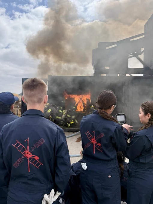 Daytime image of teens observing firefighters extinguish a fire