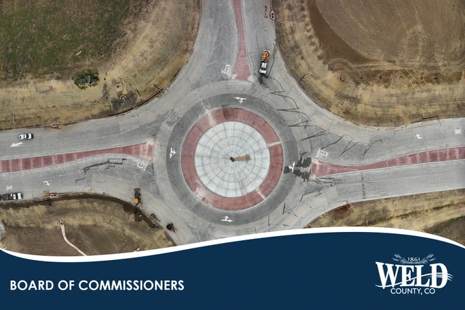 An aerial view of a roundabout being constructed. Vehicles sit in the lanes.