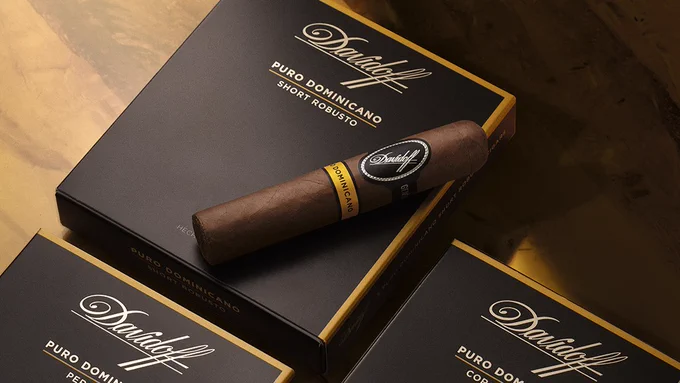 A Davidoff cigar rests on top of a Davidoff box labeled "Puro Dominicano Short Robusto." The setting includes other similar Davidoff boxes arranged on a surface. - Cigars International