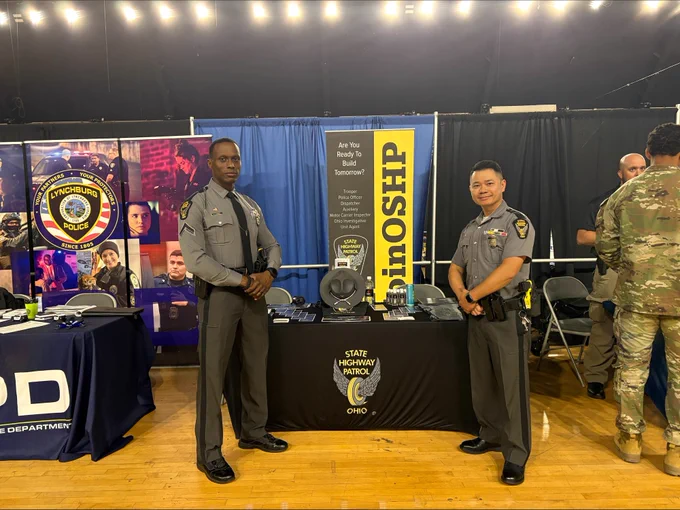 Trooper Lawrence (left) and Trooper Pham (right) attend the District of Columbia National Guard Armory Annual Career Fair for Law Enforcement. They are standing in front of a booth with OSHP information. 