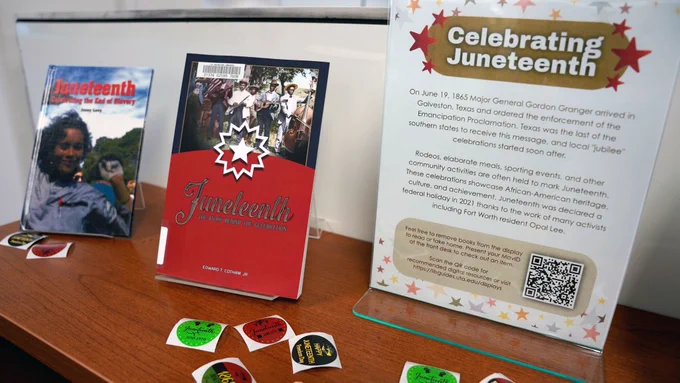 Pictured is a photo of books on display on the second floor of the U T A Central Library that talk about the history of the Juneteenth holiday. In the middle of the two books is a sign that reads "Celebrating Juneteenth."