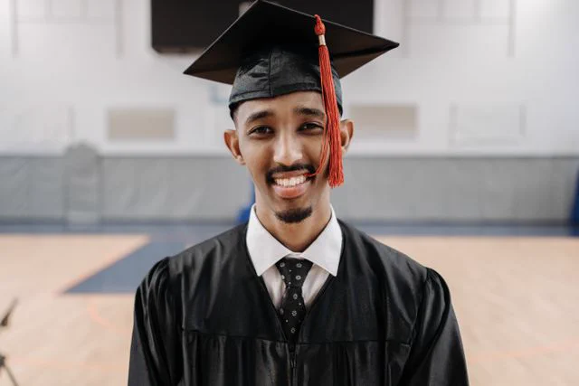 A smiling college graduate wearing his cap and gown