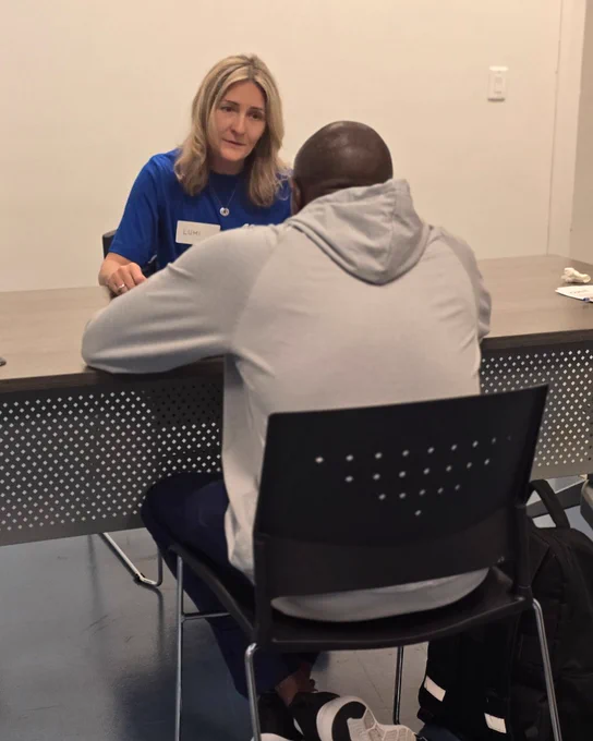 A volunteer and client are sitting across a table. The volunteer is advising the client. 