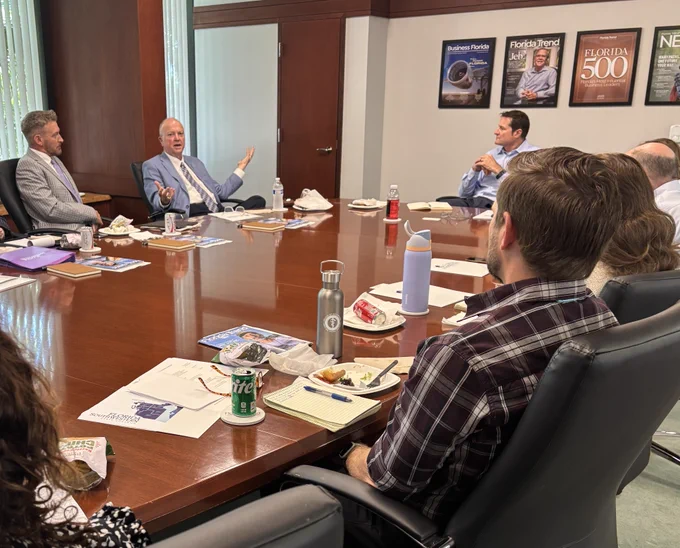 FSW President, Dr. Jeffery Allbritten, and Jason Dudley speak with Editorial Board members at Florida Trend in a large boardroom. 