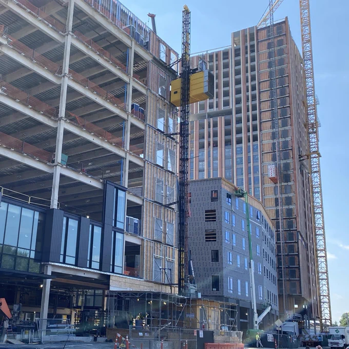 Active construction of multiple large scale buildings with large cranes and some windows being installed on the buildings.