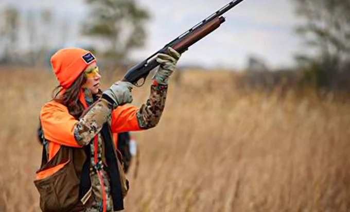Kristi Noem (former governor of South Dakota, disgraced US Secretary of Homeland Security, dog killer) posing
in a field while pointing a rifle to the sky.